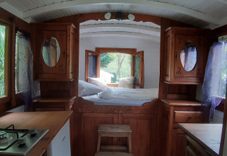 Interno della Tiny wagon al Campeggio Ushuaïa Villages Le Viaduc in Francia, con letto e cucina.