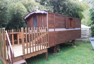 Tiny Wagon cabin at Campsite Ushuaïa Villages Le Viaduc in France with wooden deck surrounded by greenery.
