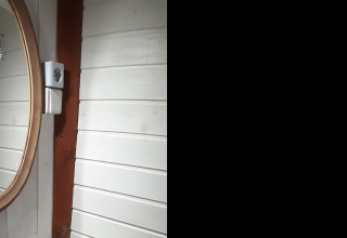 Rundt spejl og træpanelvæg i en hytte kaldet Tiny wagon på Campsite Ushuaïa Villages Le Viaduc i Frankrig.