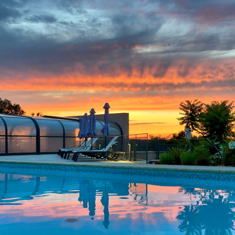 Sunset over the swimming pool at Campsite La Nouvelle Croze, a holiday park in Nouvelle-Aquitaine, France.