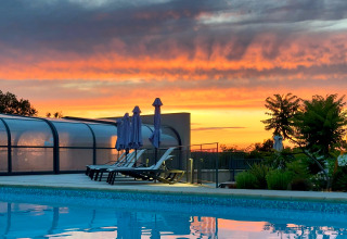 Sunset over the swimming pool at Campsite La Nouvelle Croze, a holiday park in Nouvelle-Aquitaine, France.