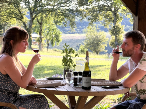 Una coppia gusta del vino a un tavolo all'aperto con vista al campeggio La Nouvelle Croze in Francia.
