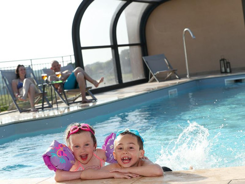 Two happy children swim in the pool as two adults relax poolside at La Nouvelle Croze, Nouvelle-Aquitaine.