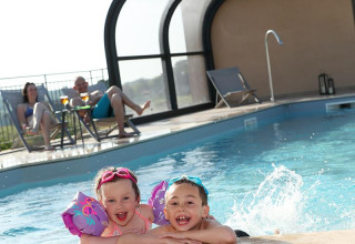 Due bambini felici giocano in piscina mentre due adulti si rilassano presso La Nouvelle Croze, Nouvelle-Aquitaine.
