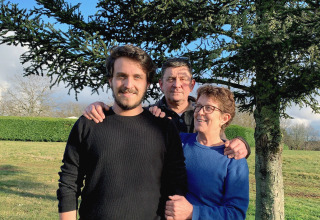 Tre persone sorridono davanti a un albero al campeggio La Nouvelle Croze, parco vacanze in Nouvelle-Aquitaine, Francia.