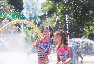 Two happy kids play in splash park fountains on a sunny day at Campsite La Nouvelle Croze in Nouvelle-Aquitaine, France.