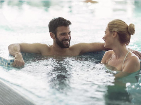 A smiling couple relaxes and shares a joyful moment together in the pool at La Nouvelle Croze campsite.