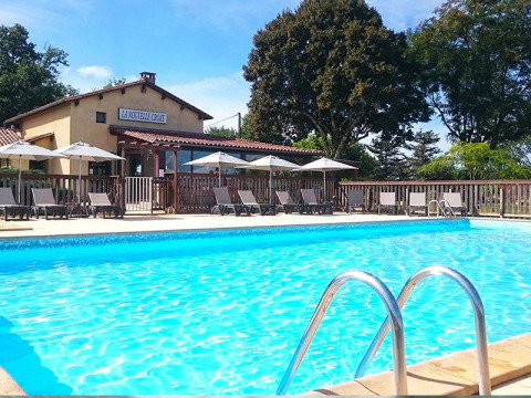 Piscina all'aperto con lettini e ombrelloni al campeggio La Nouvelle Croze in Nouvelle-Aquitaine, Francia.