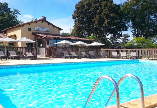Piscina all'aperto con lettini e ombrelloni al campeggio La Nouvelle Croze in Nouvelle-Aquitaine, Francia.