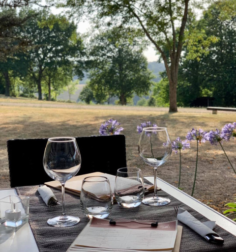 Outdoor dining table with wine glasses, menu, and scenic view at a holiday park in Nouvelle-Aquitaine, France.