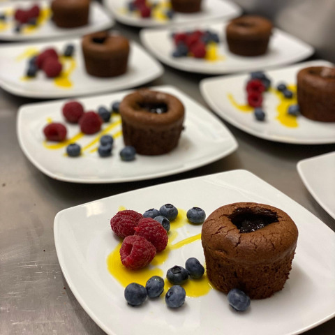 Tortini al cioccolato con lamponi e mirtilli freschi serviti su piatti bianchi pronti al ristorante.