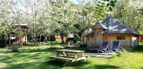 A Finnish kota hut with lounge chairs and a picnic table surrounded by trees at Ushuaïa Villages Le Viaduc.
