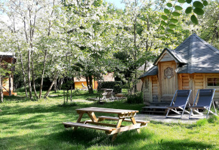 Kota finlandaise et table de pique-nique au camping Ushuaïa Villages Le Viaduc, entourés d’arbres verts.
