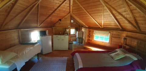 Interior of a wooden lodge in Finnish kota style with two beds, kitchenette, windows and cozy atmosphere.