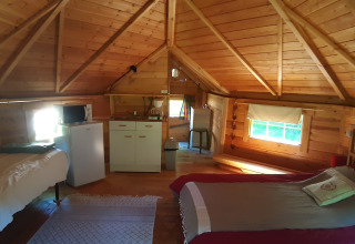 Interior of a wooden lodge in Finnish kota style with two beds, kitchenette, windows and cozy atmosphere.