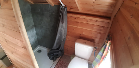 Small wooden bathroom in Finnish kota at Campsite Ushuaïa Villages Le Viaduc with shower, toilet, and window.