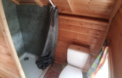 Kleines Holzbad im Finnish Kota mit WC, Dusche mit grauem Vorhang und Fenster im Campsite Ushuaïa Villages Le Viaduc.