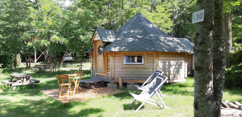 Kota finlandais au camping Ushuaïa Villages Le Viaduc en France, entouré de verdure et mobilier extérieur.