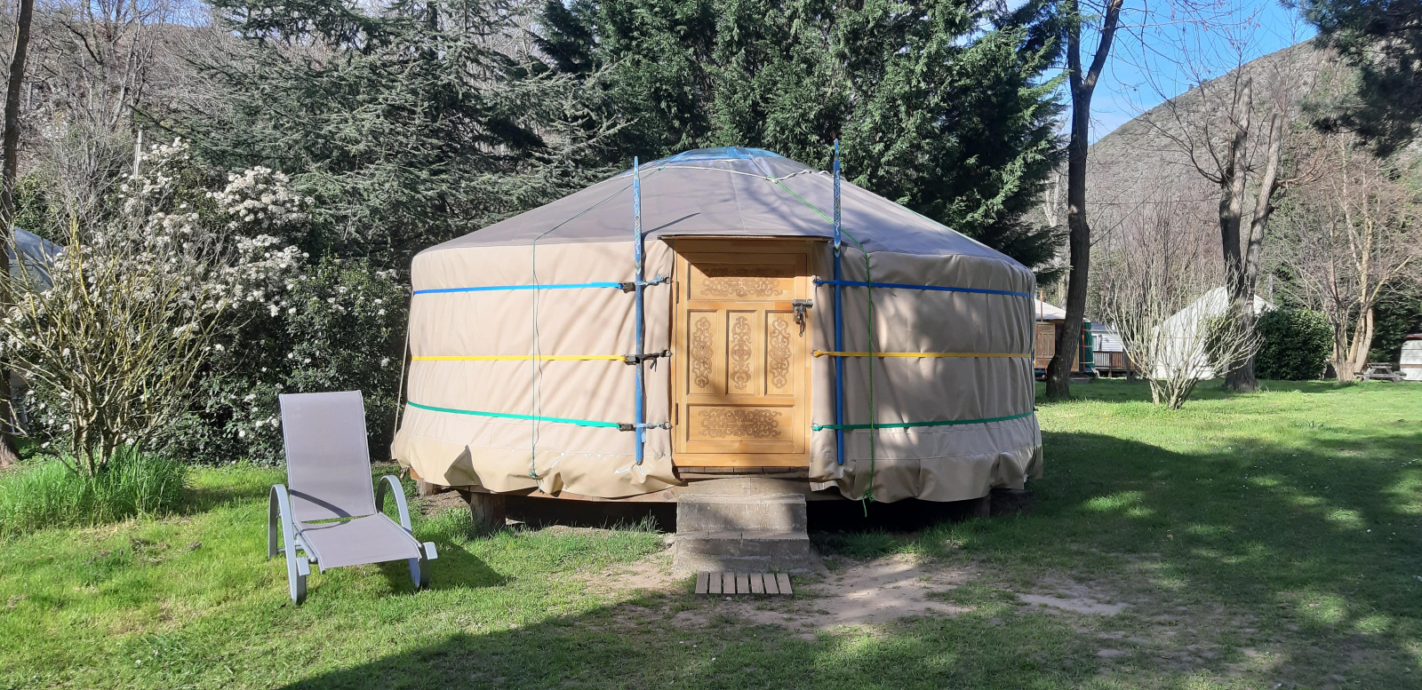 Een traditionele yurt op Ushuaïa Villages Le Viaduc camping in Frankrijk met een tuinstoel naast de ingang.