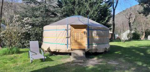 A traditional yurt at Campsite Ushuaïa Villages Le Viaduc in France with a garden chair beside the entrance.