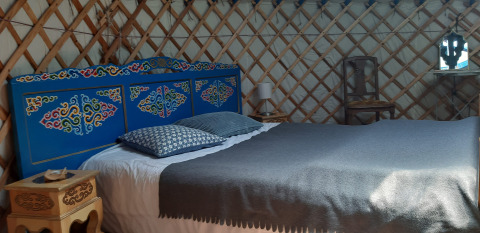 Camera yurta accogliente con testiera blu dipinta e letto matrimoniale a Ushuaïa Villages Le Viaduc, Francia.