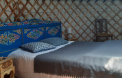 Cozy yurt bedroom with blue painted headboard and double bed at Ushuaïa Villages Le Viaduc, France.