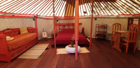 Vista interior de una yurta tradicional con muebles y camas de madera en Ushuaïa Villages Le Viaduc.