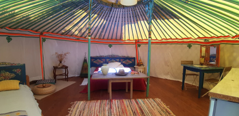 Interior view of a traditional yurt with colorful decor at Ushuaïa Villages Le Viaduc campsite in France.
