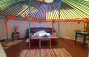 Vue intérieure d’une yourte décorée de couleurs vives au camping Ushuaïa Villages Le Viaduc en France.