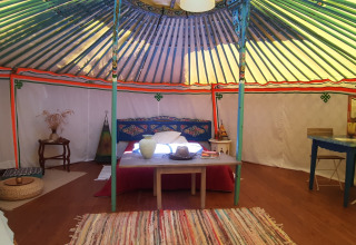 Interior view of a traditional yurt with colorful decor at Ushuaïa Villages Le Viaduc campsite in France.
