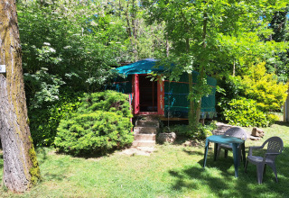 Yurta verde en Campsite Ushuaïa Villages Le Viaduc en Francia, rodeada de árboles y muebles de jardín.