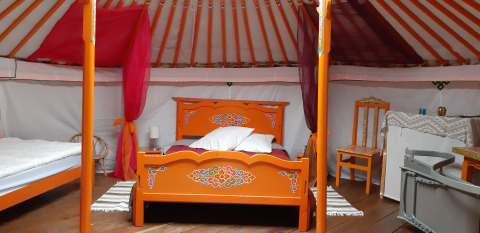 Interno di una tradizionale yurta mongola con mobili in legno colorati in un campeggio in Francia.