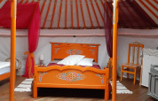Intérieur d'une yourte mongole traditionnelle avec des meubles en bois colorés dans un camping en France.