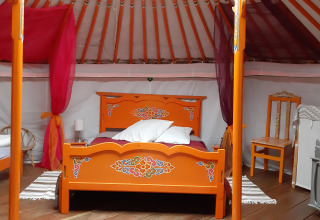 Interior of a traditional Mongolian yurt tent with colorful wooden furniture at a campsite in France.