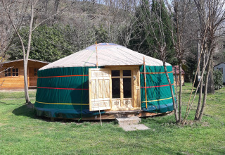 Joertent op Campsite Ushuaïa Villages Le Viaduc in Frankrijk, omringd door bomen en grasveld.