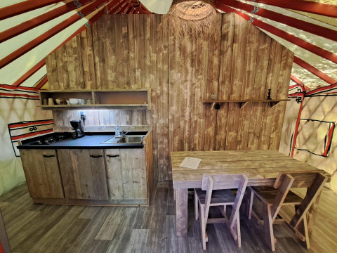 Cucina e tavolo da pranzo nella WOOD Yurt al campeggio Ushuaïa Villages Le Viaduc in Francia, stile rustico.