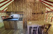 Kitchen and dining table inside WOOD Yurt at Campsite Ushuaïa Villages Le Viaduc in France, rustic decor.