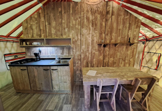 Cucina e tavolo da pranzo nella WOOD Yurt al campeggio Ushuaïa Villages Le Viaduc in Francia, stile rustico.