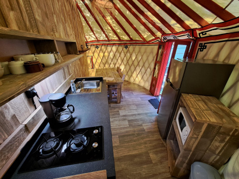 Cucina nella WOOD Yurt a Ushuaïa Villages Le Viaduc con fornello, frigorifero e tavolo da pranzo.