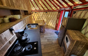 Intérieur de la WOOD Yurt au camping Ushuaïa Villages Le Viaduc avec cuisine et coin repas visibles.
