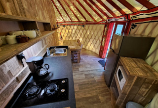 Keuken in WOOD Yurt op Ushuaïa Villages Le Viaduc met fornuis, koelkast, magnetron en eettafel.