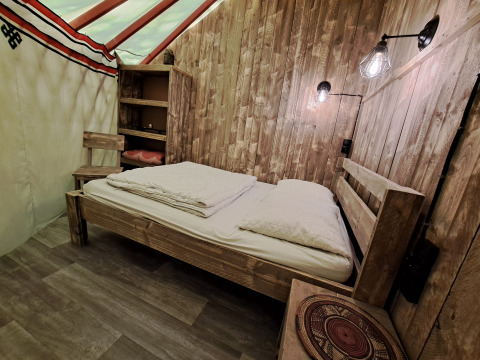 Interno in legno della WOOD Yurt al campeggio Ushuaïa Villages Le Viaduc in Francia, con letto.