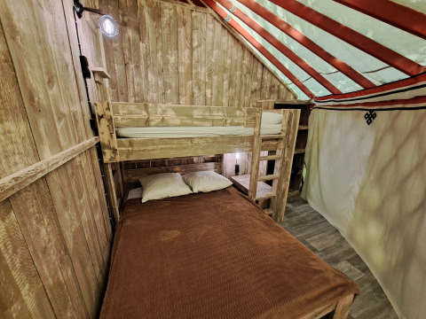 Interno della WOOD Yurt al campeggio Ushuaïa Villages Le Viaduc in Francia con letti a castello e legno.