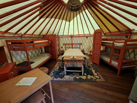 Intérieur d'une yourte traditionnelle avec lits superposés et meubles décorés dans un camping en France.
