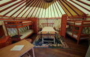 Binnenaanzicht van een traditionele yurt met stapelbedden en versierde meubels op een Franse camping.