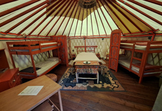 Binnenaanzicht van een traditionele yurt met stapelbedden en versierde meubels op een Franse camping.