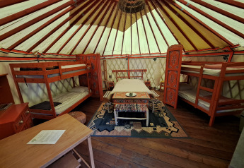 Innenansicht einer traditionellen Jurte mit Etagenbetten und verzierten Möbeln auf einem französischen Campingplatz.