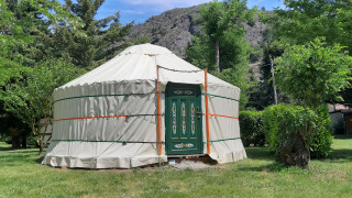 Traditional yurt tent with decorated door at Campsite Ushuaïa Villages Le Viaduc in France, surrounded by greenery.