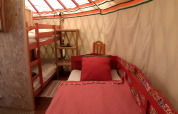 Vista interior de una yurta tradicional con litera y cama individual en Ushuaïa Villages Le Viaduc en Francia.