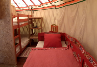 Interno di una yurta tradizionale con letto a castello e letto singolo a Ushuaïa Villages Le Viaduc in Francia.